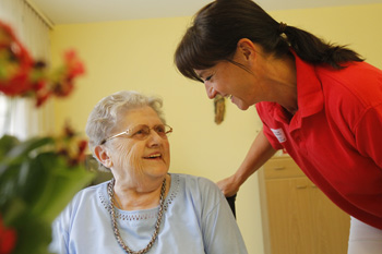 Junge Pflegerin spricht mit älterer Dame